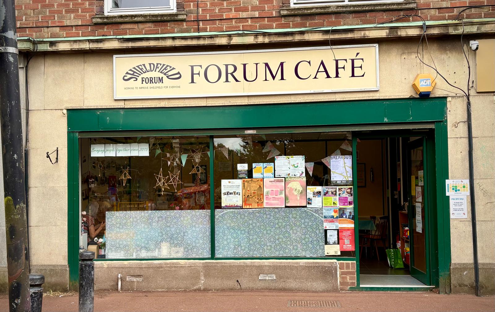 The Forum Café shopfront in Shieldfield — a cream signboard reading Forum Café above a deep-green painted frontage.